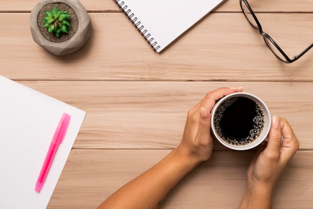 Free photo from above woman holding coffee over workspace