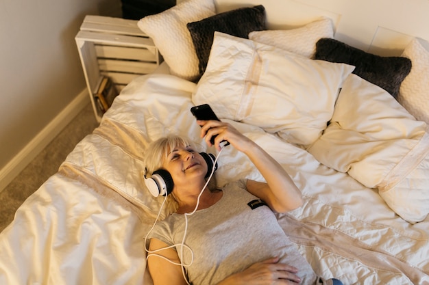 침대에서 음악을 듣고 여자 위에서