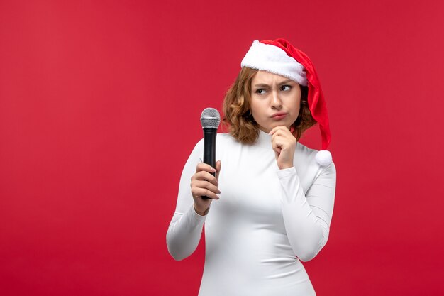 Fron view of young female holding mic on red