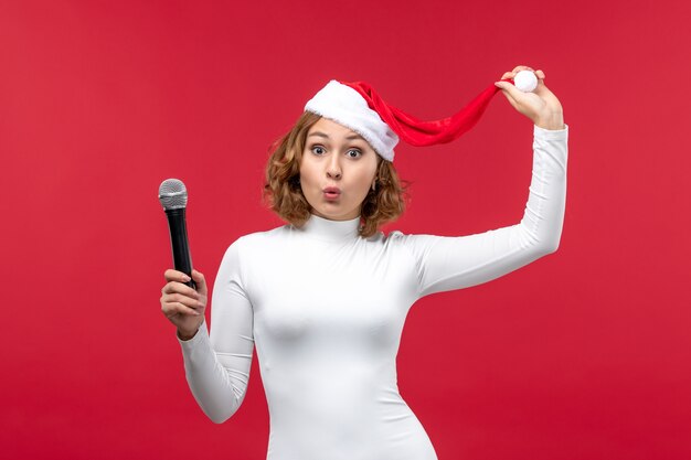 Fron view of young female holding mic on red