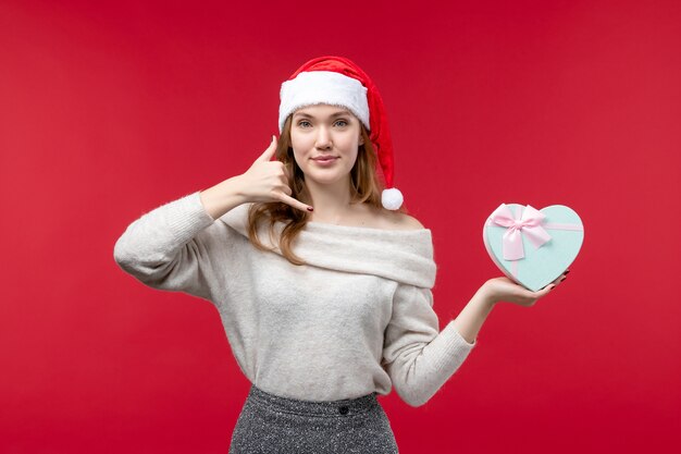 Fron view of young female holding present on red