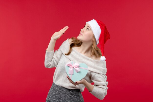 Fron view of young female holding present on red