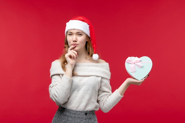 Fron view of young female holding present on red