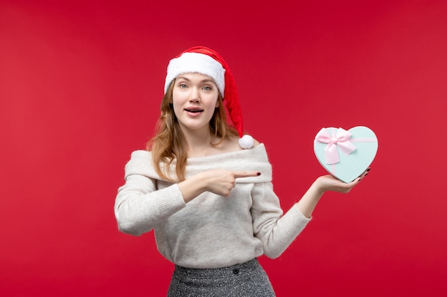 Fron view of young female holding present on red