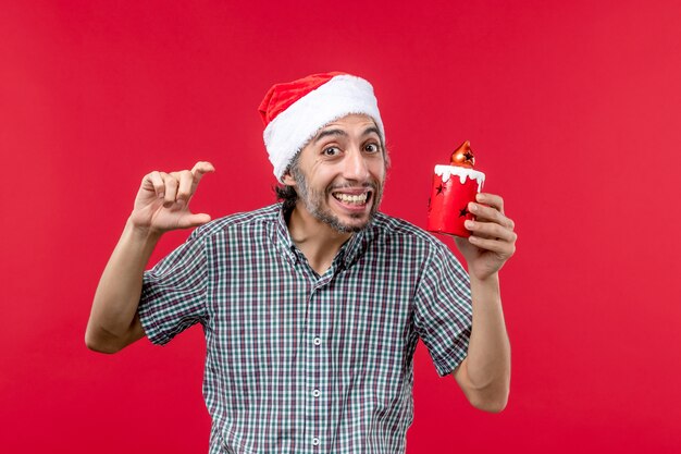 Fron view of young male holding little toy on red