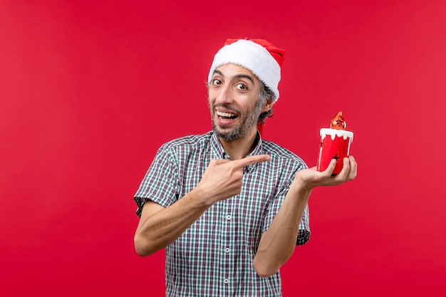 Вид спереди молодого мужчины, держащего маленькую игрушку на красном