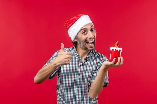 Fron view of young male holding little toy on red