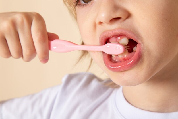 A front close up macro view blonde boy cute adorable cleaning his teeth