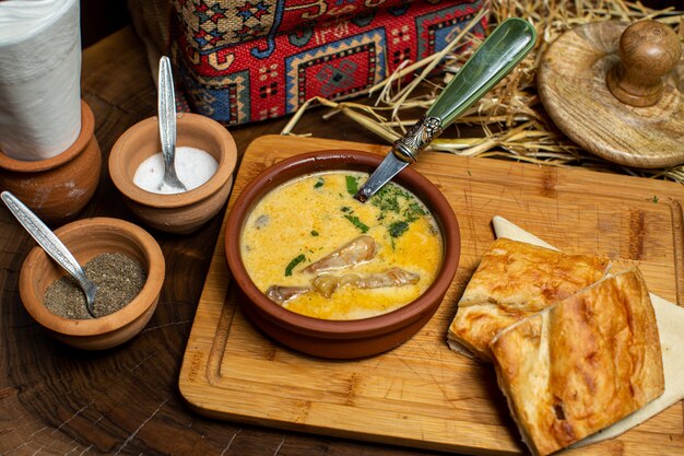 A front close up view yellow soup with greens and vegetables along with bread slices