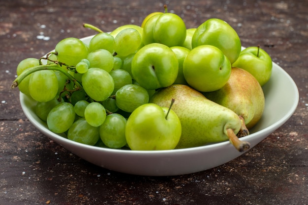 Front close view apples and grapes along with pears and cherry-plums inside plate