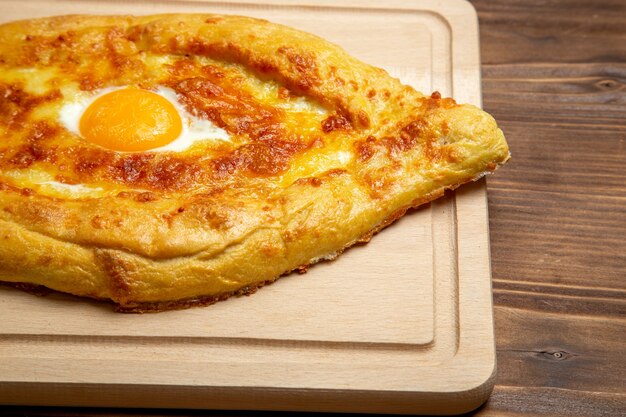 Front close view baked bread with cooked egg on wooden surface bread bun food egg breakfast dough