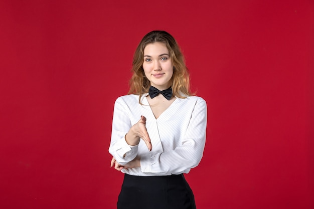 Free photo front close view of beautiful smiling waitress woman butterfly on the neck and welcoming someone on red background