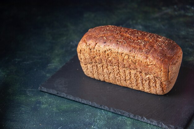 Front close view of black bread on black board on mixed colors distressed background