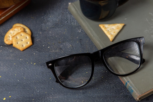 Front close view black sunglasses with crisps on the grey surface