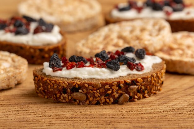 Front close view bread toasts with cream and dried fruits on wood