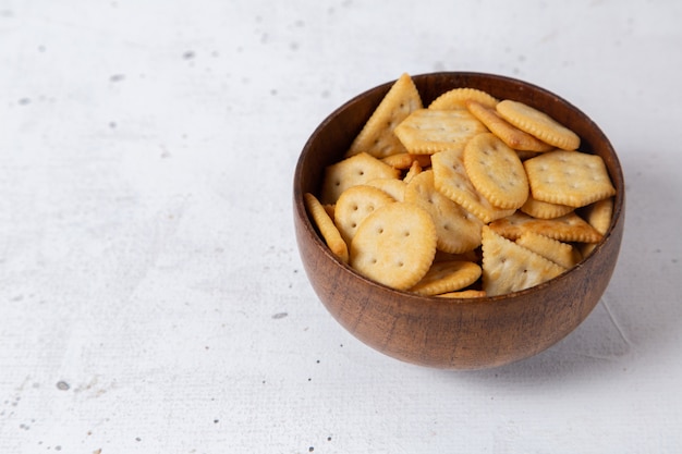 Front close view brown metallic plate with salted crackers on the white surface