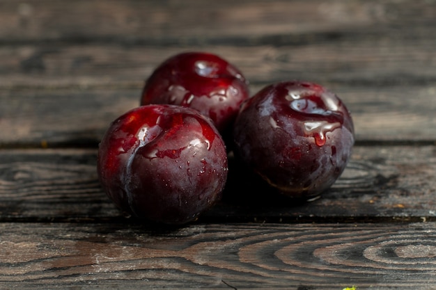 Vista ravvicinata della borgogna prugne mellow e aspro frutti sul fondo rustico marrone vitamina frutta freschezza estiva