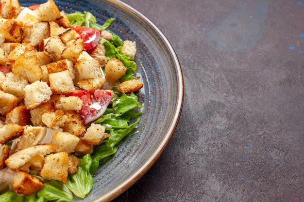 Front close view caesar salad with sliced vegetables and rusks on dark surface