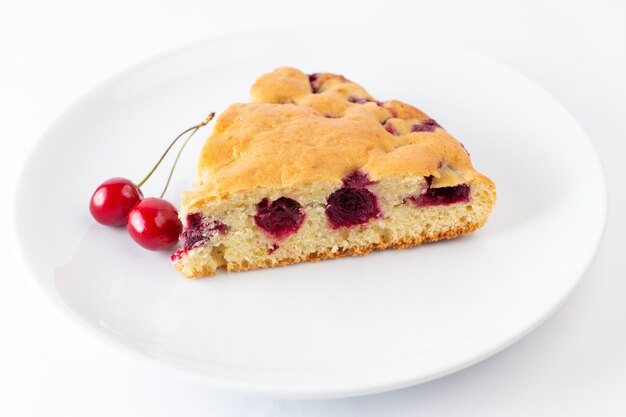 Front close view cherry cake slice inside white plate on the white surface
