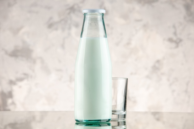 Front close view of closed and filled with milk glass bottle and cup on white smoke background with free space