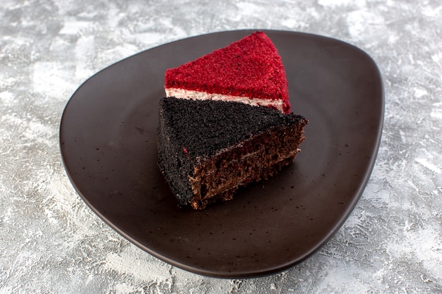 Front close view colored cake slices chocolate and fruit cake pieces inside brown plate on the grey surface