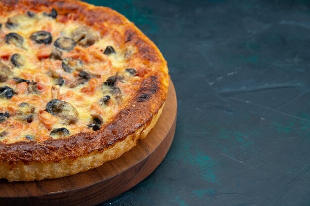 暗い机の上にチーズとオリーブとおいしい調理済みピザの正面のクローズビュー