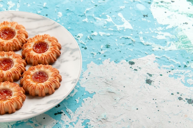 Front close view delicious cookies round formed with jam inside plate on light blue surface cookie sugar sweet biscuit cake