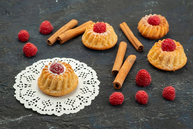 Biscotti deliziosi di vista ravvicinata anteriore con lamponi rossi freschi e cannella sul dolce della bacca della frutta del biscotto di superficie scura