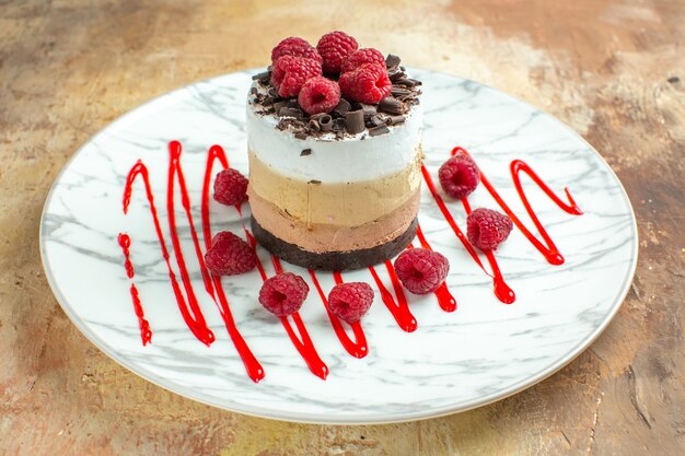 Front close view delicious creamy cake inside plate with raspberries on brown table