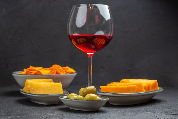 Front close view of delicious snacks for wine in a glass goblet on a black background