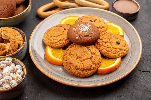 Front close view delicious sugar cookies with fresh sliced oranges on dark