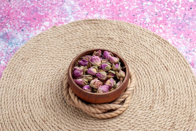 正面のクローズビューはピンクの机の上にロープで小さな花を乾燥させました。花の色の写真の背景。