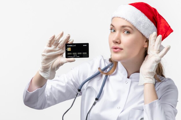 Front close view of female doctor holding bank card on a white wall