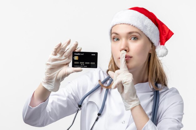 Front close view of female doctor holding bank card on white wall