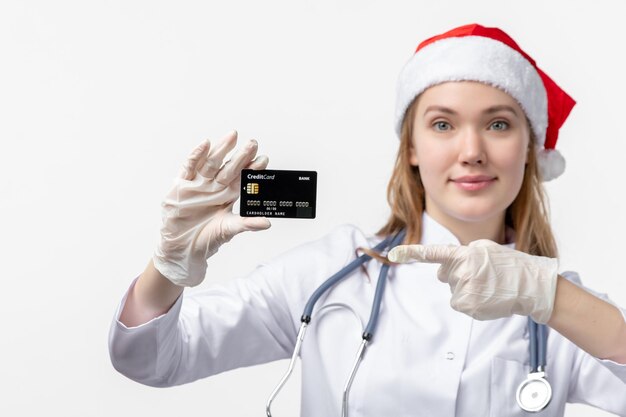 Front close view of female doctor holding bank card on white wall