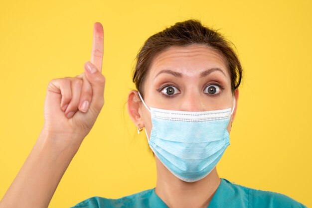 黄色の背景に滅菌マスクで正面の女性医師