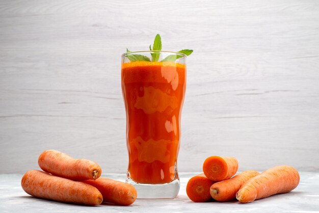 Front close view fresh carrot juice inside long glass with leaf and along with fresh carrots vegetable 