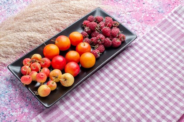 Front close view of fresh fruits inside black form on pink surface