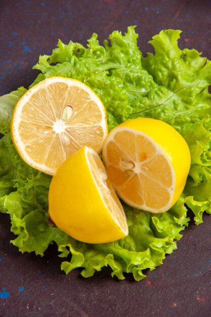 暗いスペースにグリーン サラダを添えた新鮮なレモン スライスを正面から見た図