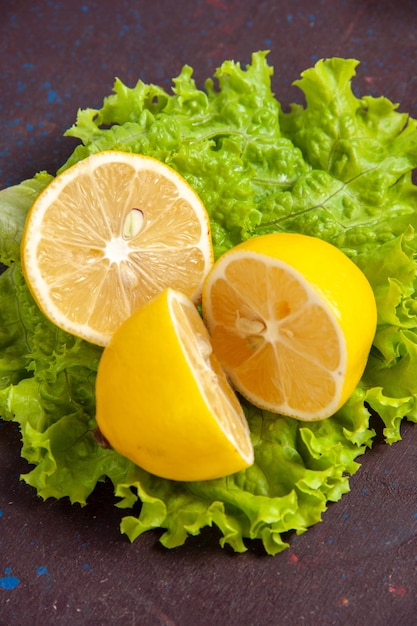 Front close view fresh lemon slices with green salad on a dark space