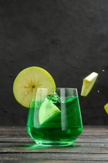 Front close view of fresh natural delicious juice in a glass served with apple limes on black background