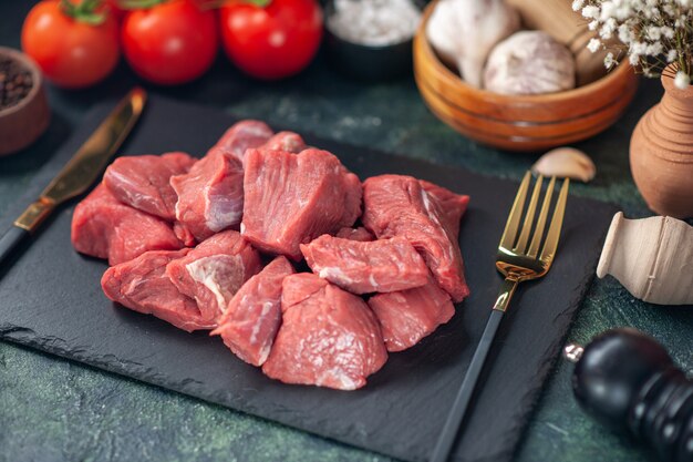 Front close view of fresh raw chopped meats and cutlery set on wooden board