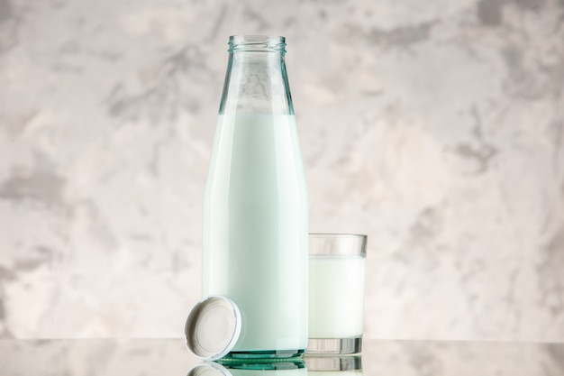 Вид спереди крупным планом стеклянной бутылки, наполненной крышкой чашки молока на фоне белого дыма со свободным пространством