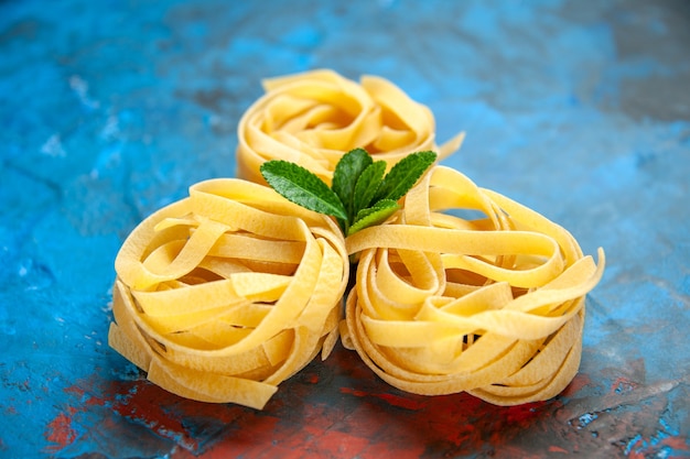 Foto gratuita vista frontale ravvicinata delle tagliatelle fresche fatte in casa con verde su sfondo blu