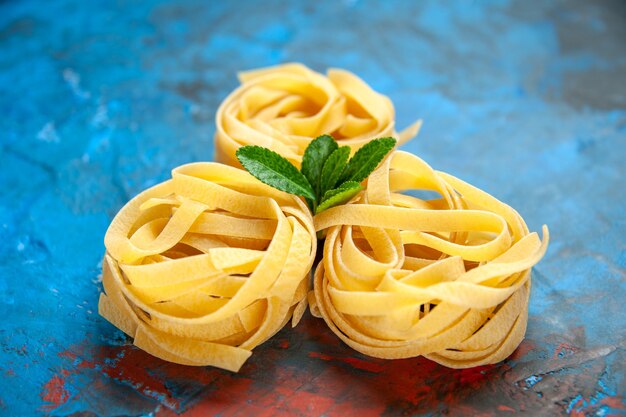 Front close view of homemade fresh tagliatelle pastas with green on blue background