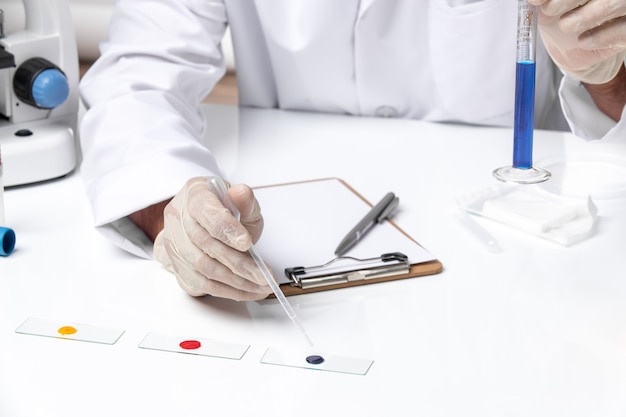 Front close view male doctor in white medical suit on white desk