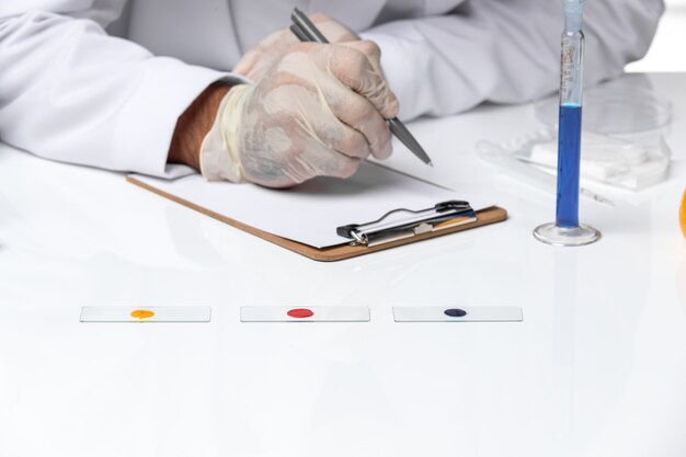 Front close view male doctor in white medical suit with mask due to covid writing on white space