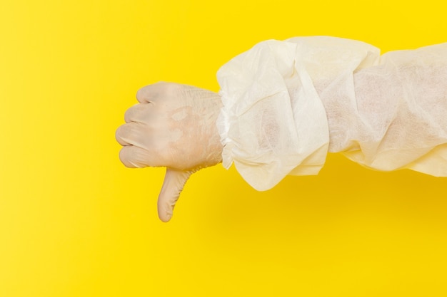 Front close view of male scientific worker in special protective suit showing unlike sign on yellow wall