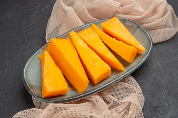 Front close view of natural fresh yellow cheese on a half folded towel on a black background