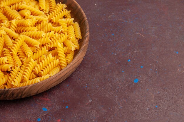 Front close view raw italian pasta inside wooden tray on dark space